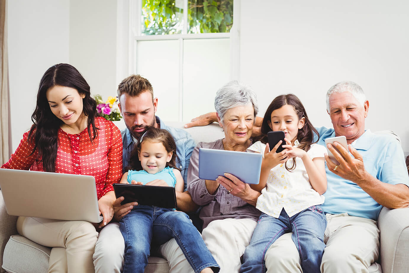 A family using laptops, tablets and phones together at home